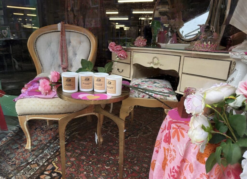 Petersham Cottage Candles displayed in a Bridgerton-themed Valentine’s window display, with pink roses, vintage furniture and a dressing table backdrop